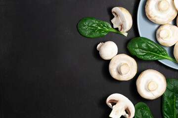 Obraz na płótnie Canvas Raw mushrooms champignons on a black background.