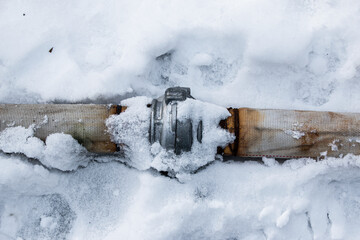 Winter. Everything is covered with snow. Leak in the connection of pipes pumping water out of the...