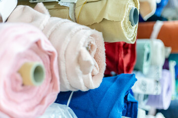 rolls of colored fabrics on a shelf in a warehouse