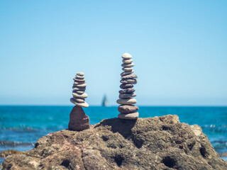 Zen stone pyramid by the mediterranean sea with sailboat at the bottom