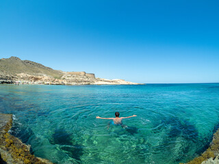 Young man relaxes and swims in the water of the Mediterranean Sea in Cabo de Gata, Almeria