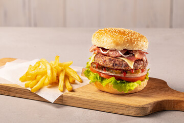 Close-up home made beef burger and fries on wooden board, clear light background