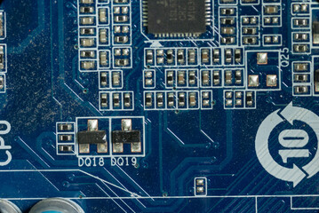 several board microcircuits and transistors on the motherboard in a dusty personal computer close-up