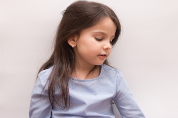 Obraz premium Little girl sitting looking to the side on a white background