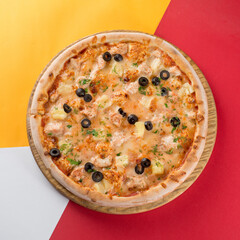Whole round pizza on a yellow and orange background. Concept for pizzerias
