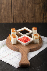 Dragon sushi rolls with eel and pickled ginger on wooden board