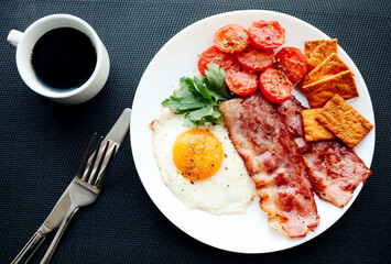 English breakfast - fried eggs, herbs, tomatoes, bacon and crackers