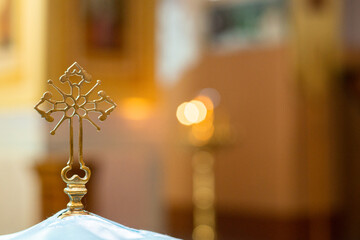 photo of a beautiful cross on a font for babies against a background of many candle lights
