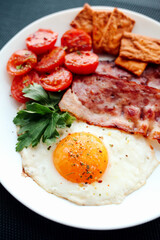English breakfast - fried eggs, herbs, tomatoes, bacon and crackers