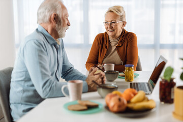 Happy mature couple communicating while having breakfast at dining table