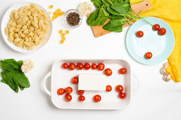 step-by-step preparation and ingredients for oven-baked feta cheese with tomatoes and pasta, pepper garlic on a light background top view, trend recipe
