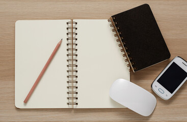 Blank Spiral Note Pad, computer mouse, cellphone and Pencil on Wood Background.