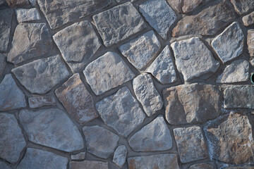 Obraz premium randomly shaped rocks cemented together by mason to create solid rock exterior wall of home chimney or retaining wall sample f masonry stones wall stones put together like puzzle pieces horizontal 