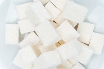 granulated sugar cubes on a plate sweets light background