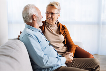 Happy mature couple sitting on sofa and communicating