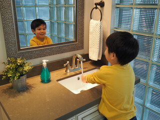 A boy smiles while he washes his hands