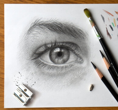 Realistic drawing of a human eye. Monochrome hand drawing. The process of working on the artist’s desktop with art materials.