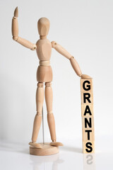 The wooden man raised his hand, and under his left hand he has cubes with the inscription - GRANTS