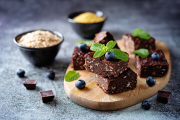 Dark chocolate oats millet porridge brownies decorated with blueberries and mint leaves