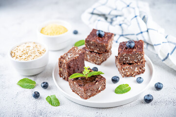 Dark chocolate oats millet porridge brownies decorated with blueberries and mint leaves