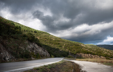 Low angle shot of road and green hills with overcast sky
