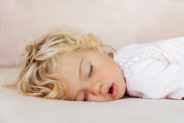 Baby girl sleeping under pink blanket.