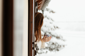 Femme prenant le thé à la fenêtre sous la neige