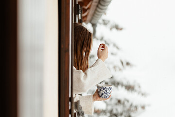 Femme prenant le café à la fenêtre sous la neige