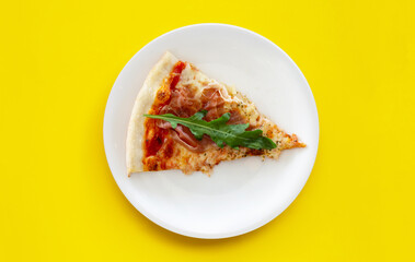 Pices of Pizza on white plat on yellow background.