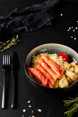salad with salmon in a plate on a black textured background