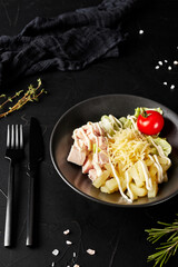 salad with pineapple chicken and cheese in a black plate on a dark textured background