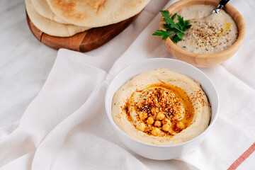 Hummus in a bowl and Baba ghanoush, pita on a light table. Mediterranean appetizer, vegetarian healthy food concept. Top view, flat lay, copy space.