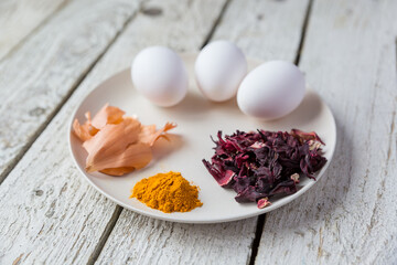 Natural dyes for Easter eggs. Chicken eggs, hibiscus tea, onions, turmeric are on the plate.