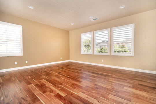 Bright beige large empty room with wood floor, molding and windows. Modern bright room, interiors.