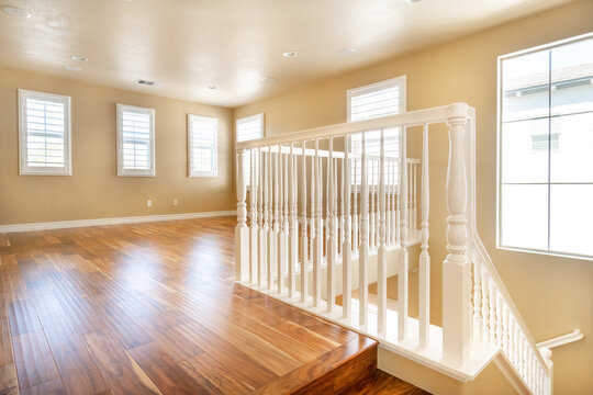 Large empty room with wood floor, molding and windows and stairs. Modern bright room, interiors.