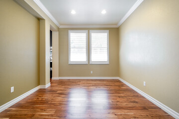 Bright beige large empty room with wood floor, molding and windows. Modern bright room, interiors.