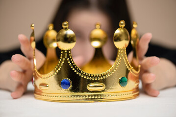 Woman holding a golden crown in the hands. Get a power. First place winner.