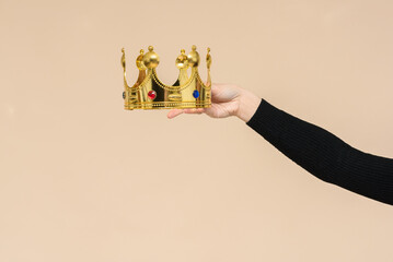 Female hands is wearing a golden crown on the copy space. Award ceremony.