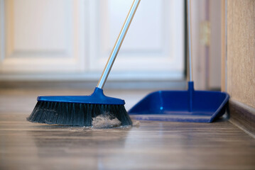 Broom brush and dustpan on the floor. Home cleaning.