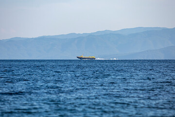 Speed boat, cruising at calm sea against a blue sky.