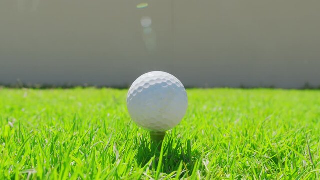 Golfer placing golf ball on the tee at golf course. Closeup.