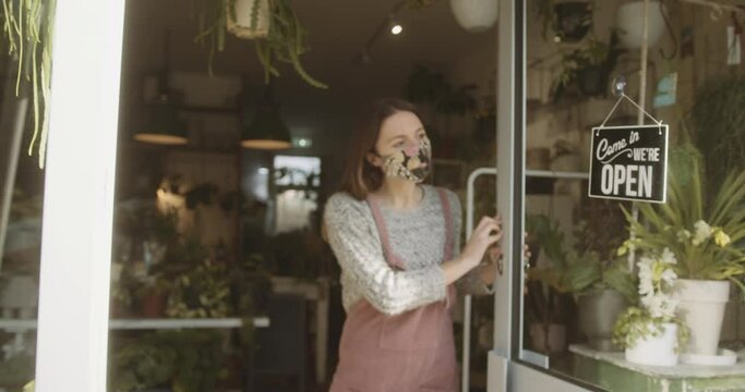 Small business entrepreneur wearing face mask open store door for customers during coronavirus pandemic.