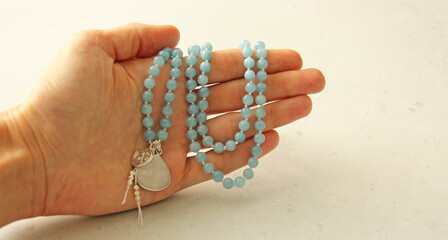 Rosary mala 108 beads from natural stones Aquamarine lie in girl's hand. Author's jewelry from natural stones, Buddhism, matra, prayer, rosary from stones for prayer and beauty. Rosary in hand