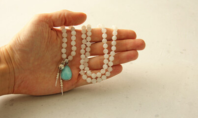 Rosary mala 108 beads from natural stones Moonstone lie in girl's hand. Author's jewelry from natural stones, Buddhism, matra, prayer, rosary from stones for prayer and beauty. Rosary in hand