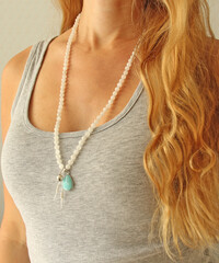 Rosary mala 108 beads from natural stones Moonstone are worn on a girl in a grey shirt. Author's jewelry from natural stones, Buddhism, matra, prayer, rosary from stones for prayer and beauty