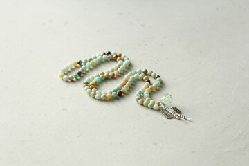 Rosary mala 108 beads from natural stones amazonite lie on light modern background. Author's jewelry from natural stones, Buddhism, matra, prayer, rosary from stones for prayer, beauty. Long beads