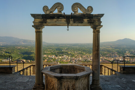 The ancient water well in front of Palazzo Colonna Barberini with panorama with hills near Rome on the background, Palestrina, Italy