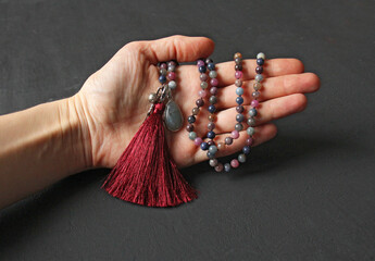 Rosary mala 108 beads from natural stones Sapphire lie in girl's hand. Author's jewelry from natural stones, Buddhism, matra, prayer, rosary from stones for prayer and beauty. Rosary in hand