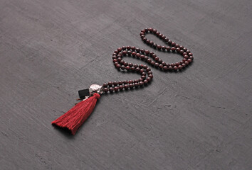 Rosary mala 108 beads from natural stones Garnet lie on black modern background. Author's jewelry from natural stones, Buddhism, matra, prayer, rosary from stones for prayer, beauty. Long beads
