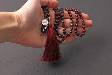Rosary mala 108 beads from natural stones Garnet lie in girl's hand. Author's jewelry from natural stones, Buddhism, matra, prayer, rosary from stones for prayer and beauty. Rosary in hand